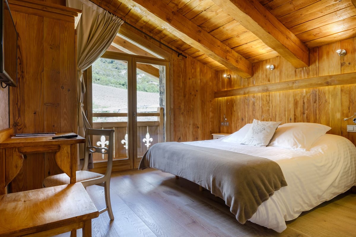 Een houten kamer met een bed, een bureau en een stoel.