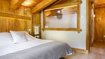 Una habitación de madera con una cama, una ventana con panel de vidrio esmerilado y techo de madera.