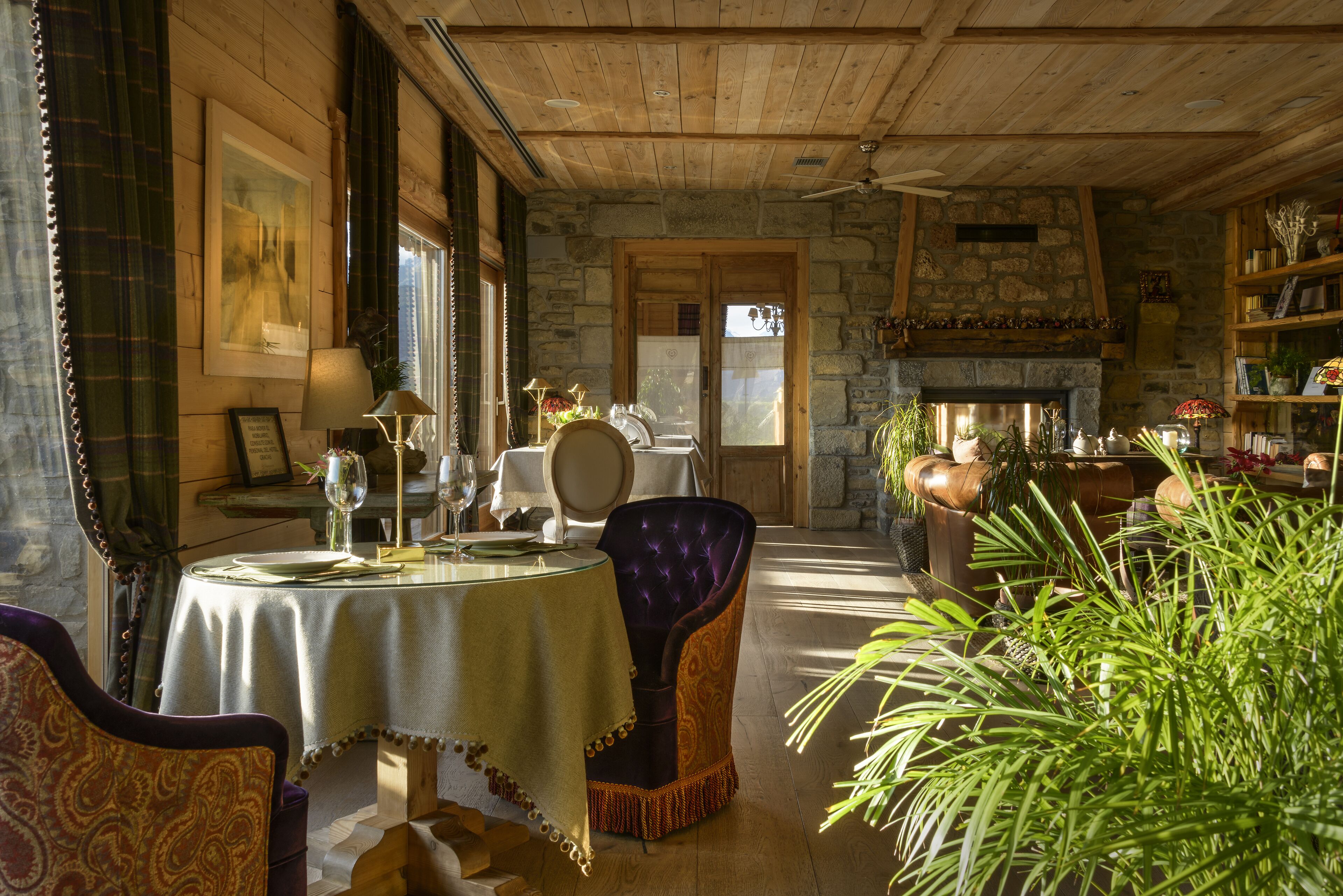 Un'accogliente sala da pranzo con camino in pietra, soffitto in legno e tavolo apparecchiato.