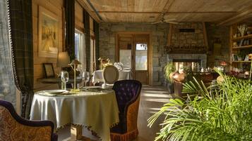 Un'accogliente sala da pranzo con camino in pietra, soffitto in legno e tavolo apparecchiato.