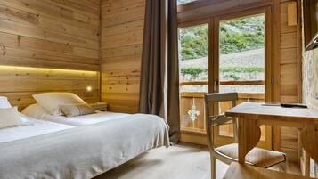 A wooden cabin room with a bed, a table, and a chair.