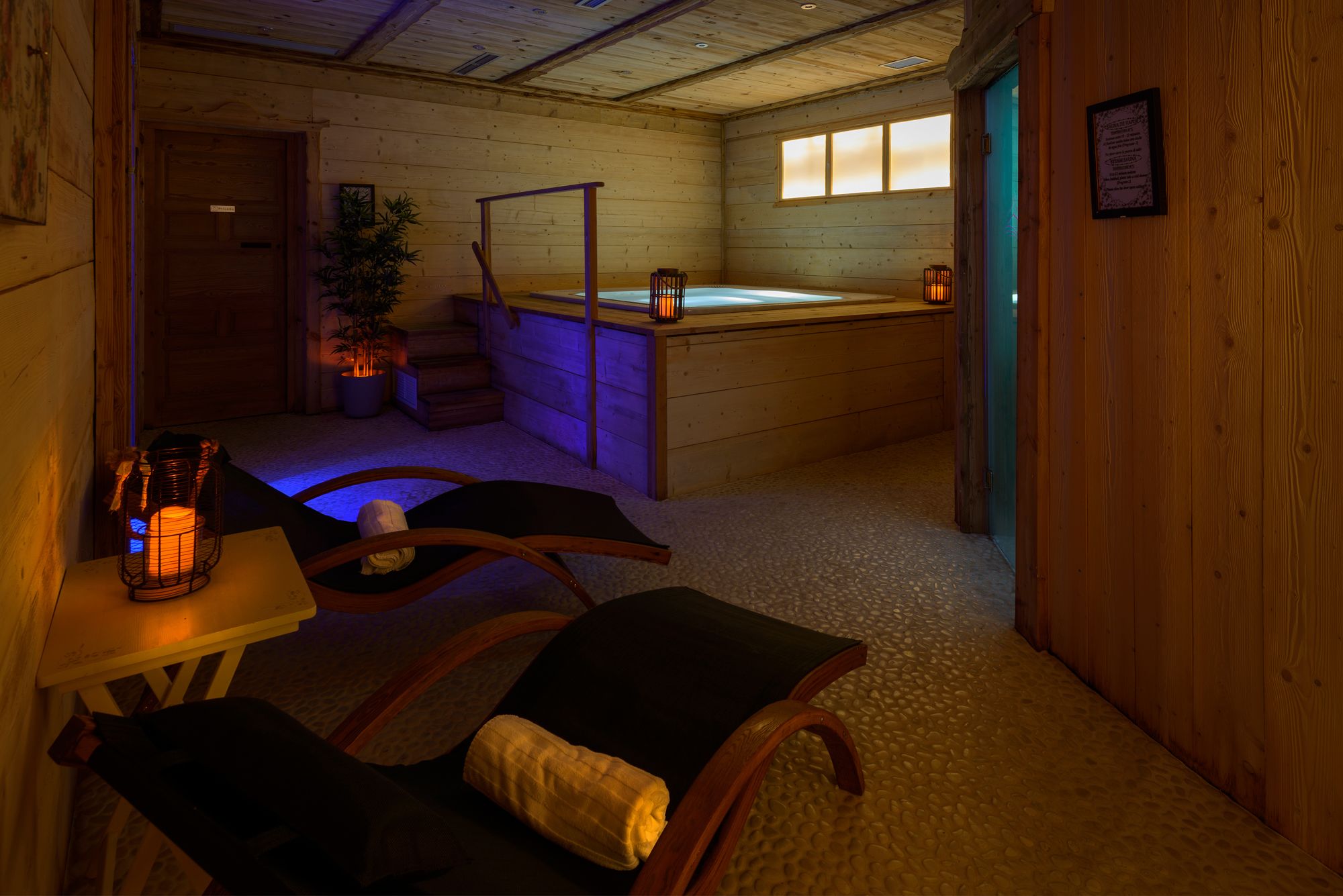 A cozy room with a wooden interior, a small table with chairs, a hot tub, and a staircase leading to another level.