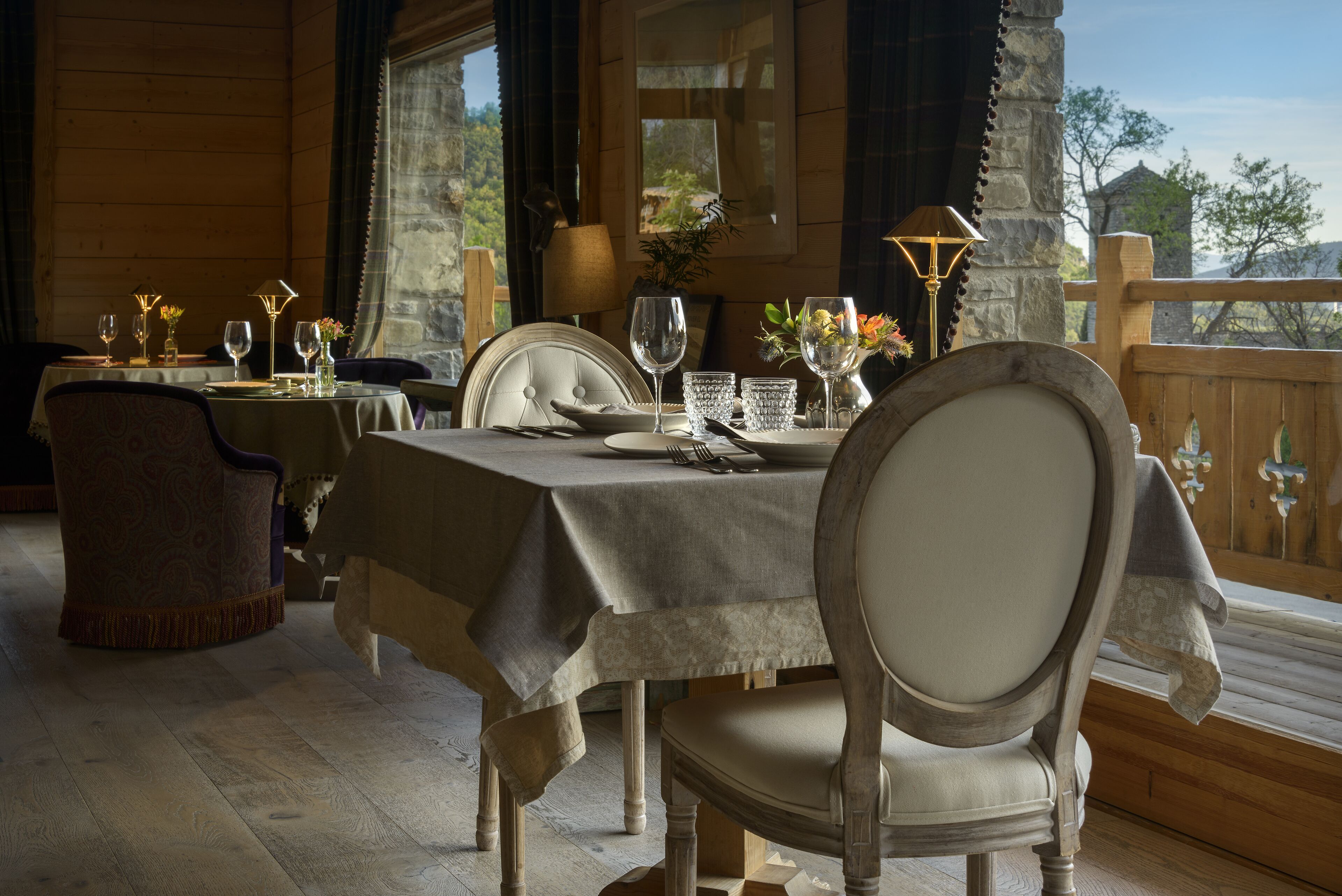 A dining area with a table set for two, chairs, and a view of the outdoors.