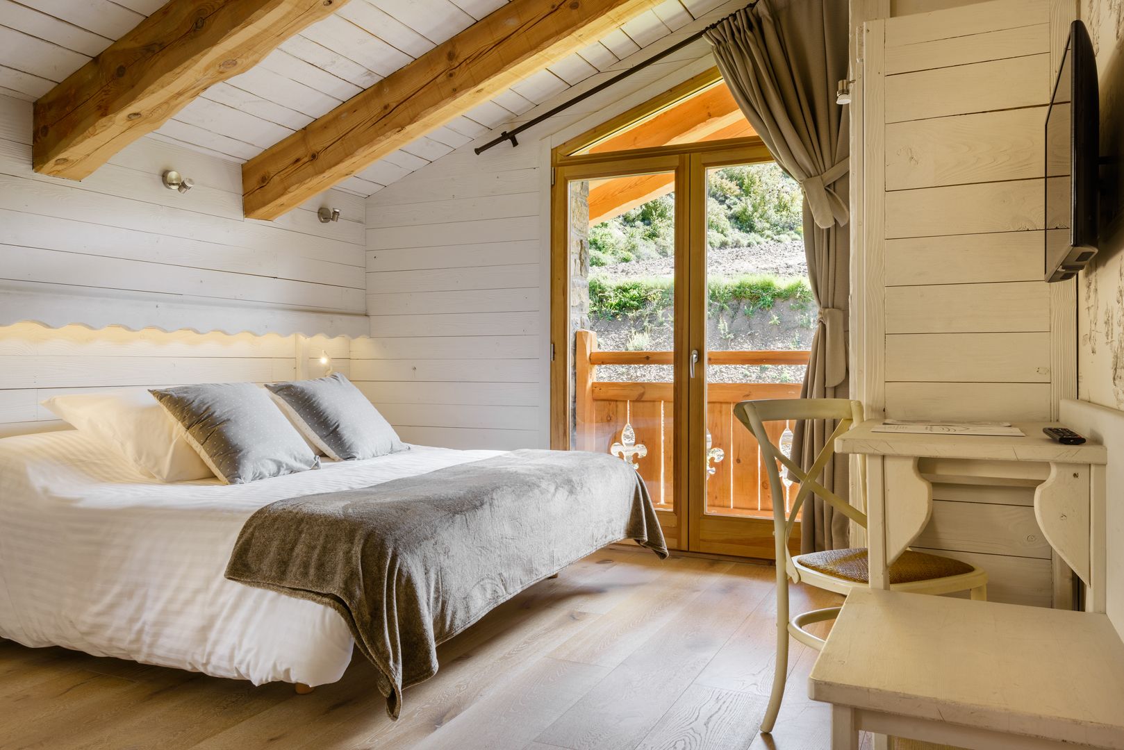 Um quarto aconchegante com uma cama, uma escrivaninha de madeira e uma televisão.