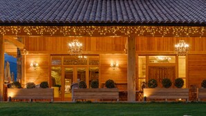A wooden building with a tiled roof, outdoor seating, and string lights.