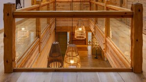 A wooden interior with a glass ceiling, wooden railings, and pendant lighting.