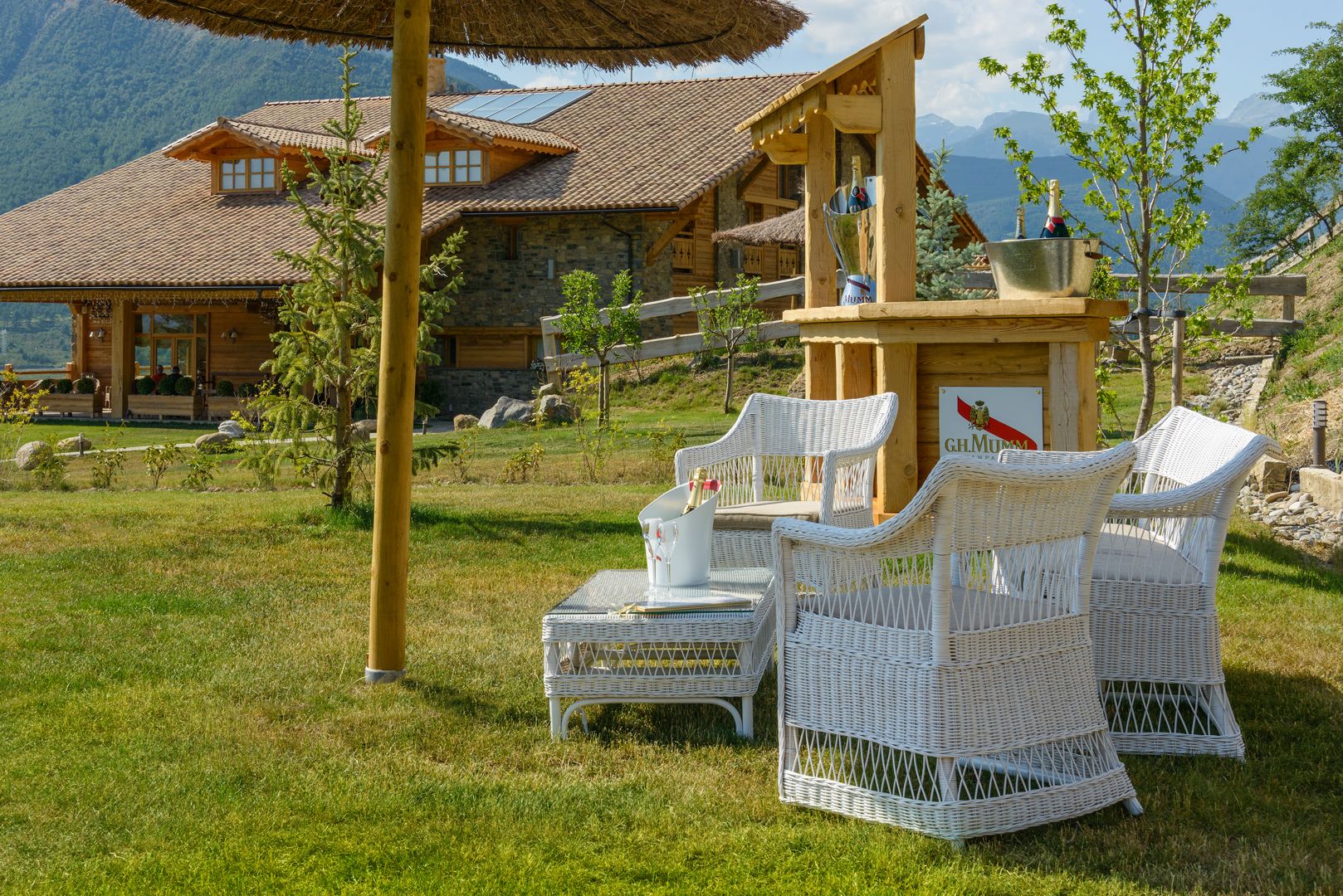 Een chalet met buitenzitplaatsen, een houten tafel en een fles champagne.
