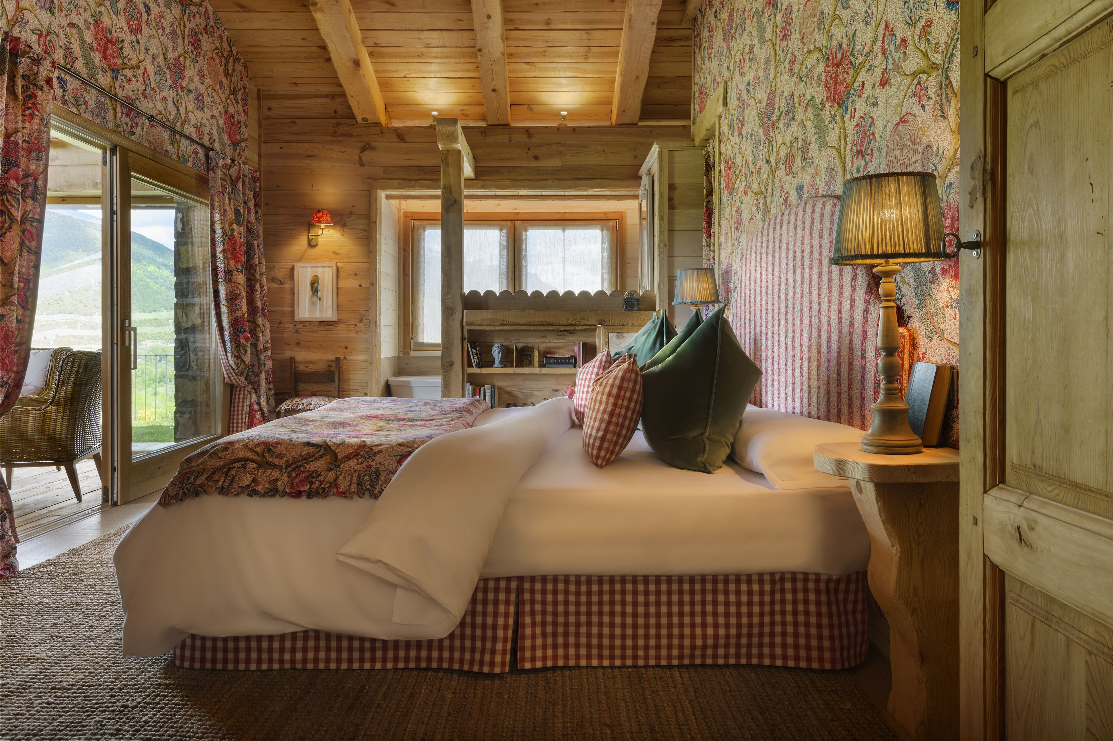 Un dormitorio acogedor con una cama grande, techo de madera y vistas al exterior a través de un ventanal.