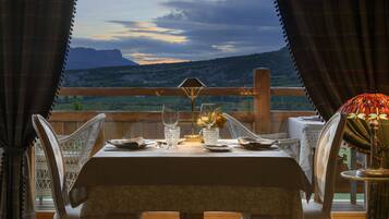 Mesa de comedor para dos personas con vistas a montañas al fondo.