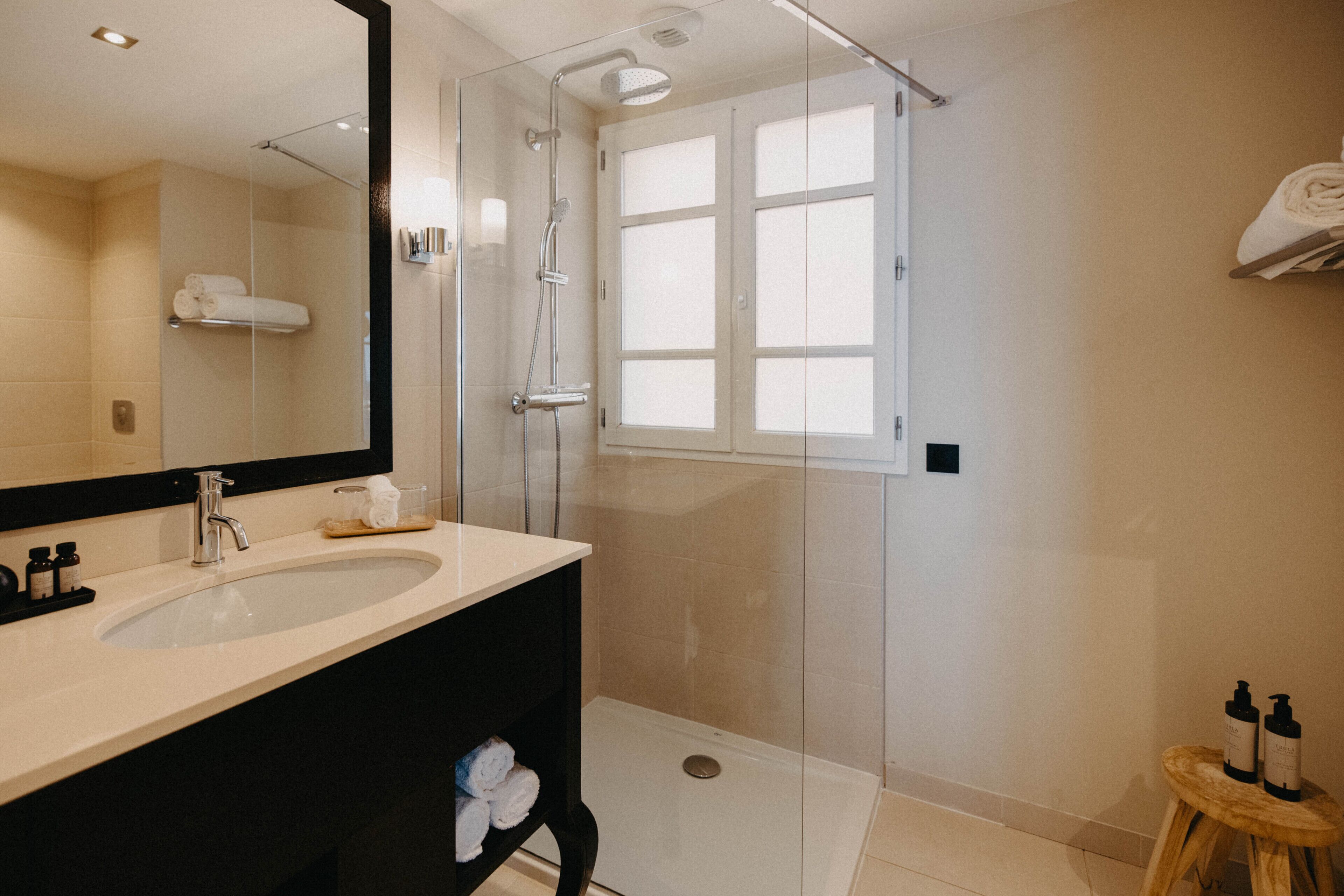 A modern bathroom with a glass-enclosed shower, a large mirror, and a vanity with a sink.