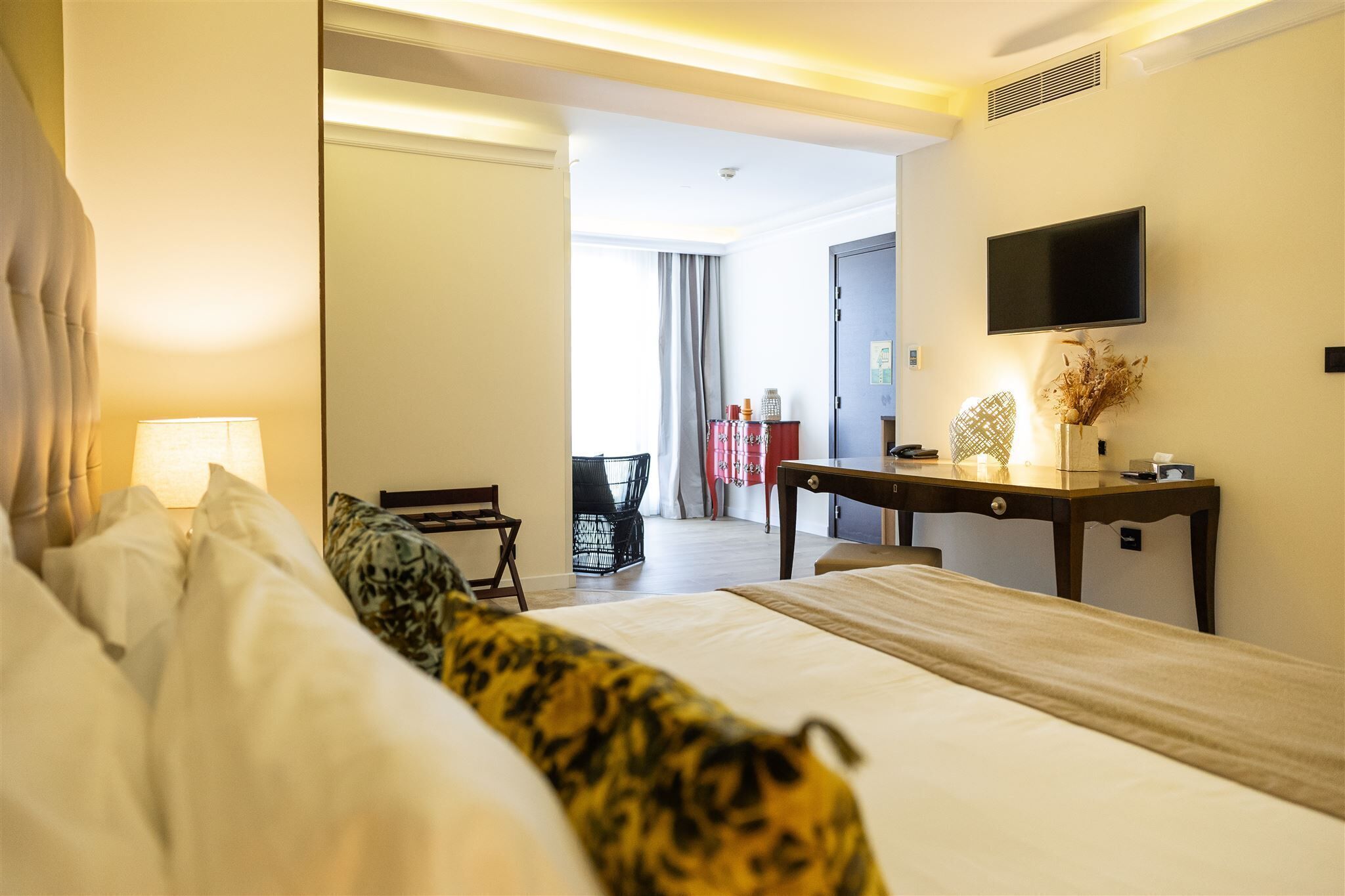 Hotellihuone, jossa on sänky, työpöytä, tuoli, televisio ja näkymä ulos.