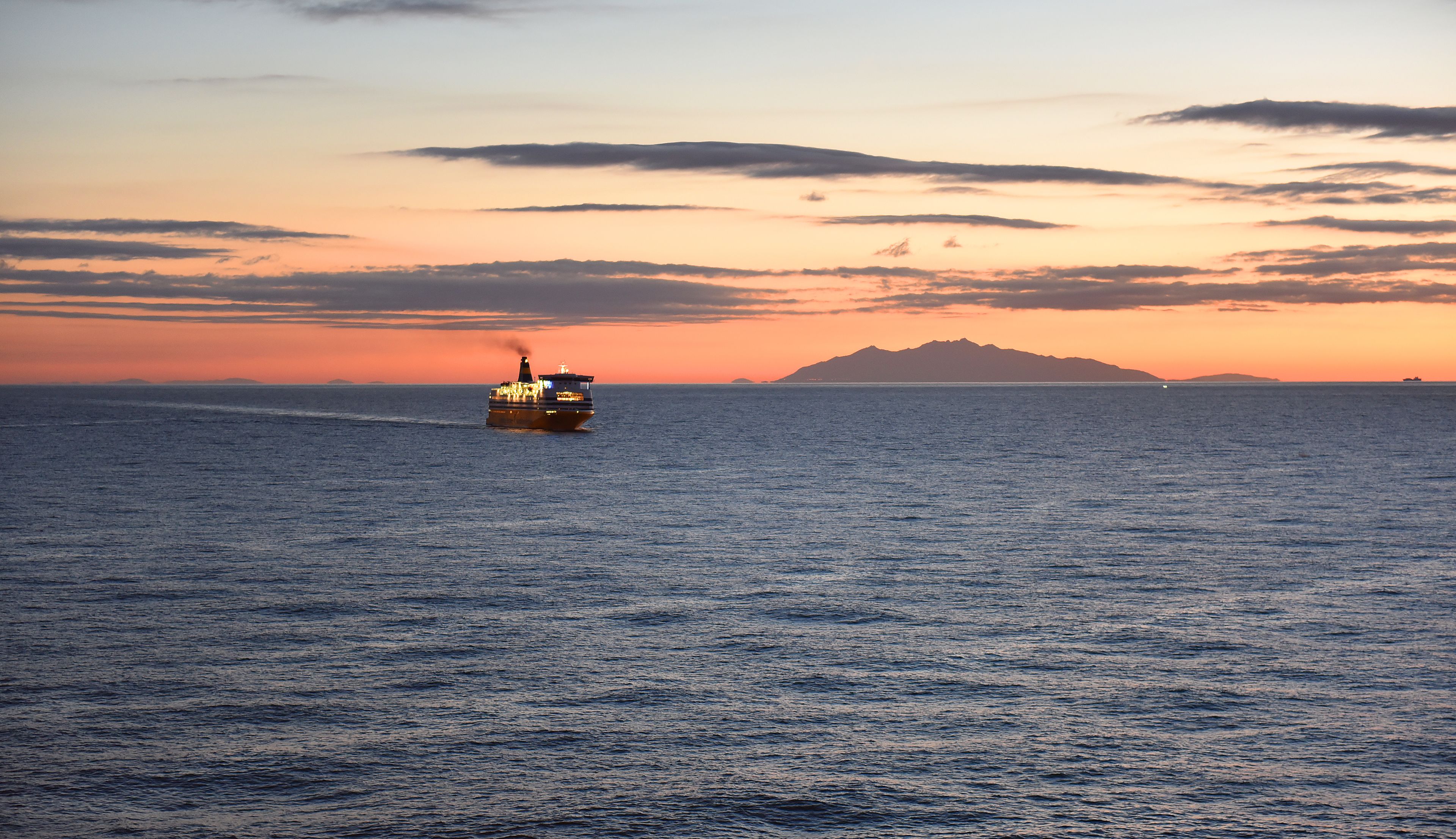 Un barco en el océano con un atardecer de fondo.
