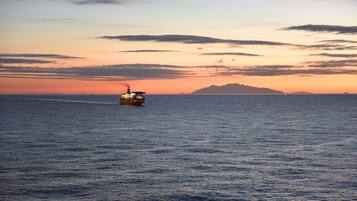 Un barco en el océano con un atardecer de fondo.
