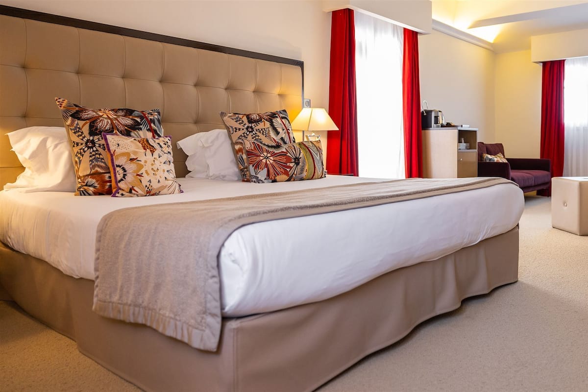 A hotel room with a large bed, a desk, and a chair.
