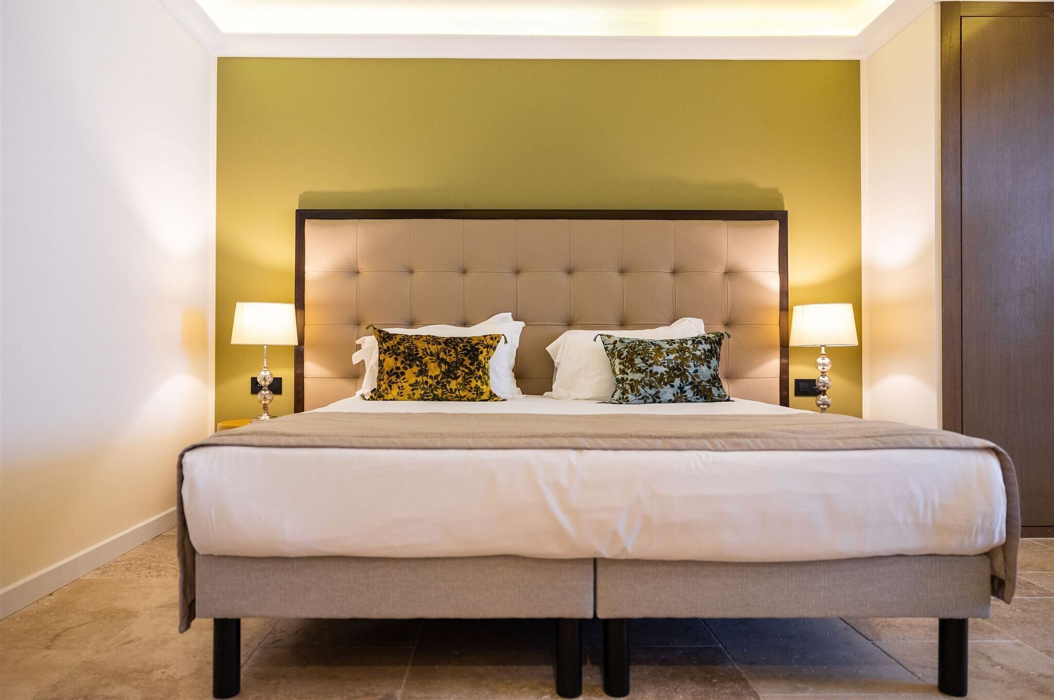 A large bed with a tufted headboard, two bedside lamps, and decorative pillows.