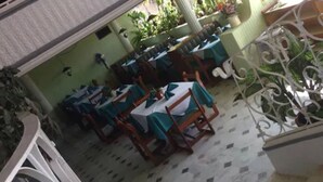 A dining area with tables and chairs, some covered with green tablecloths. - Motel La Fortuna (Fresnillo)
