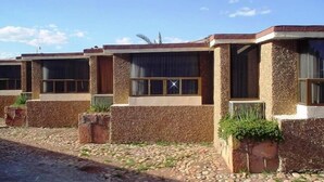 A row of stone buildings with large windows and a paved walkway. - Motel La Fortuna (Fresnillo)
