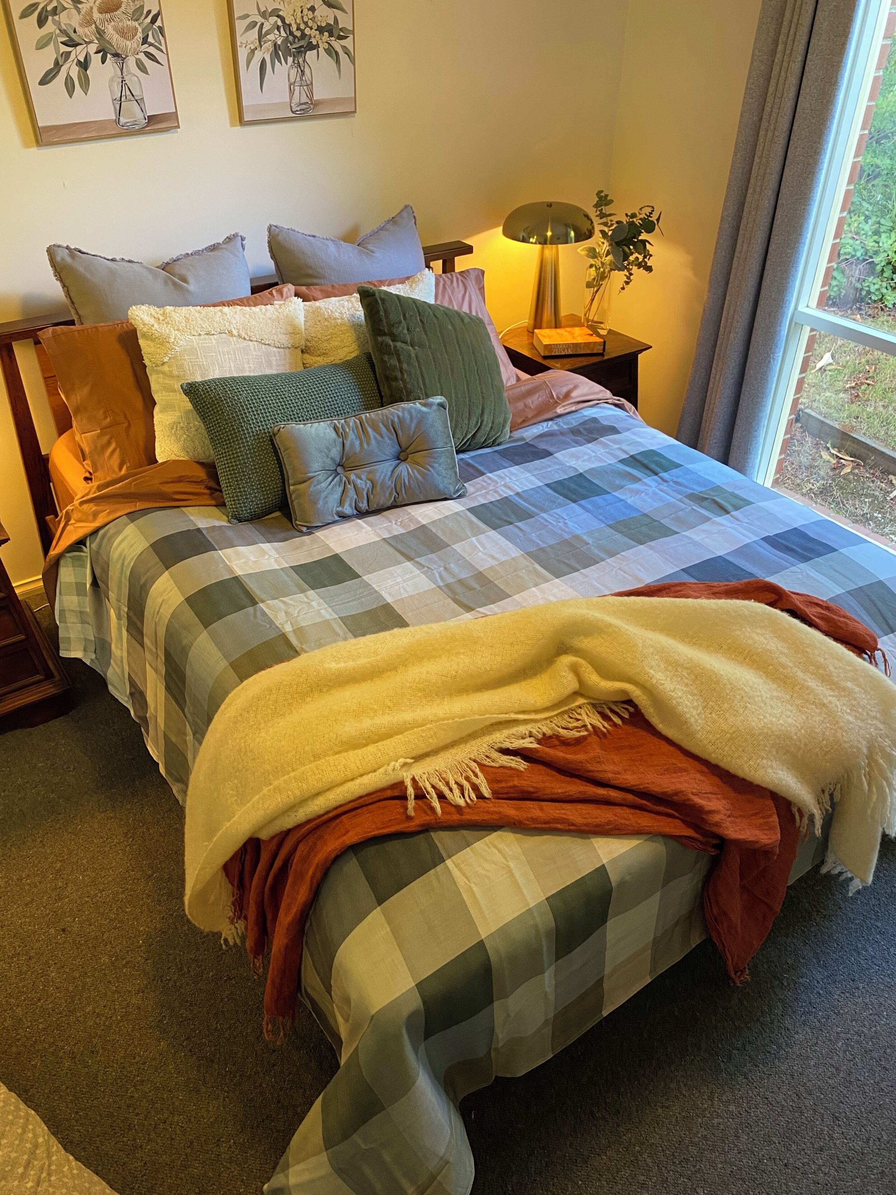 A neatly made bed with a checkered bedspread, multiple pillows, and a blanket.