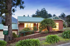 A brick building with a green roof, surrounded by greenery and a tree. - Annie's Escape in Warburton (Warburton)