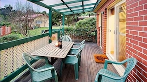 A covered patio with a wooden table and four green plastic chairs. - Annie's Escape in Warburton (Warburton)