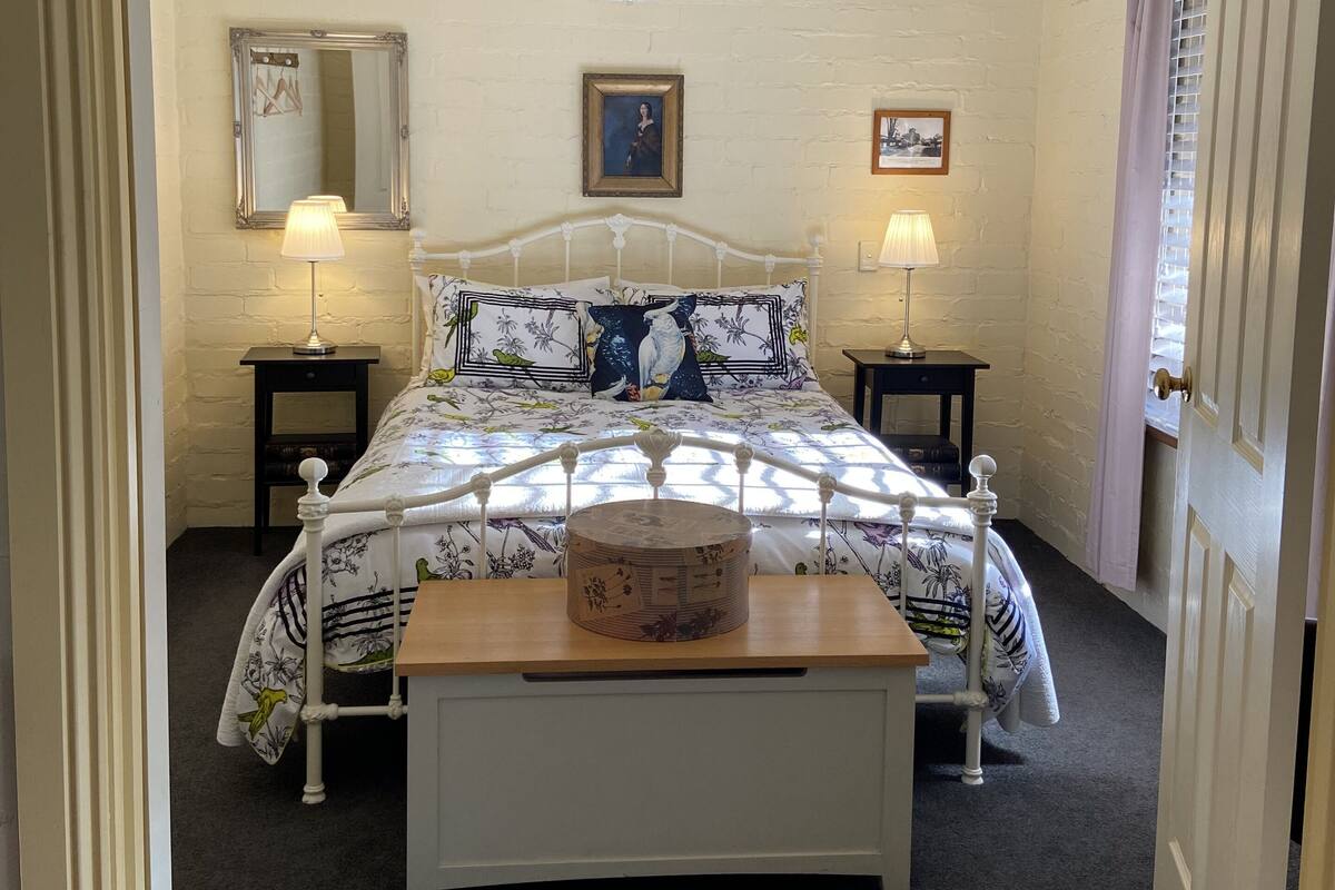 A bedroom with a bed, bedside lamps, a ceiling fan, and a wooden nightstand.