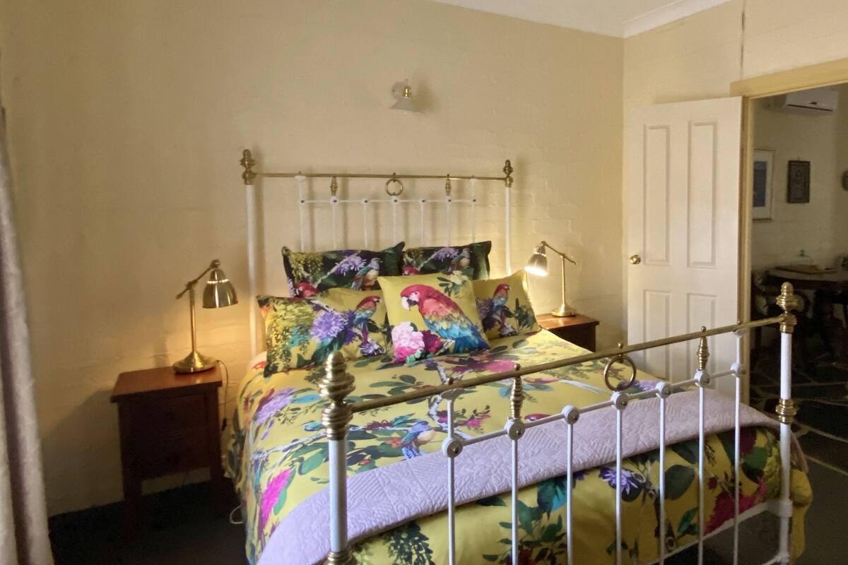 A bed with a metal frame, floral bedding, two bedside lamps, and a nightstand.