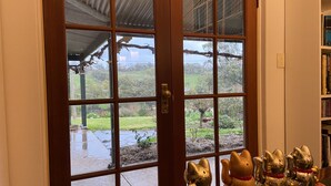 A wooden door with glass panels, a bookshelf with books, and a garden view. - Battunga Cottages (Watervale)