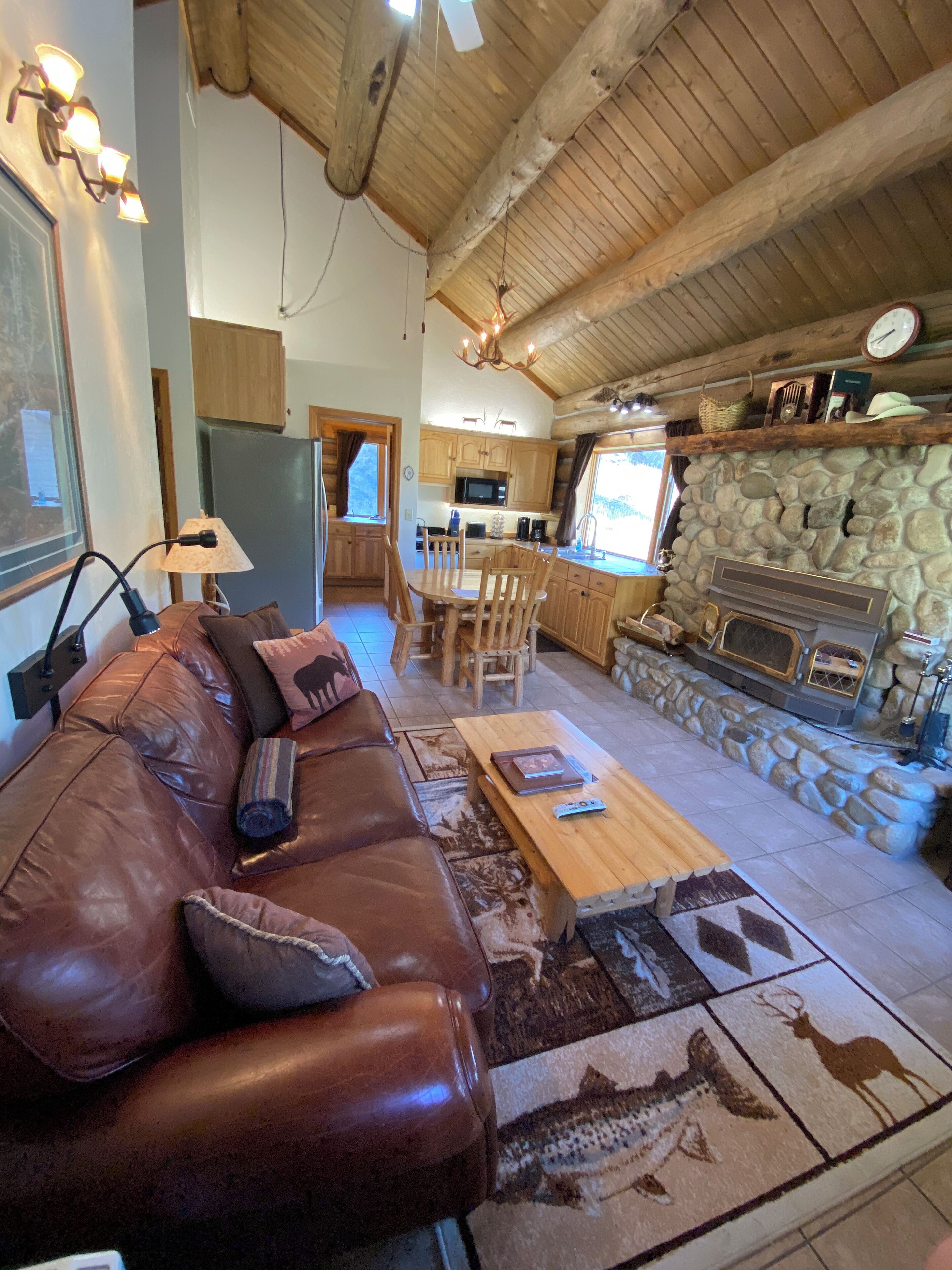 A cozy living room with a leather sofa, a wooden coffee table, and a stone fireplace.
