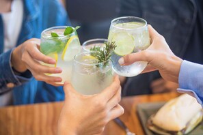 A group of people holding glasses of a beverage with lime and mint, suggesting a social setting.