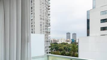 Un edificio alto con vistas a otros edificios y árboles al fondo.