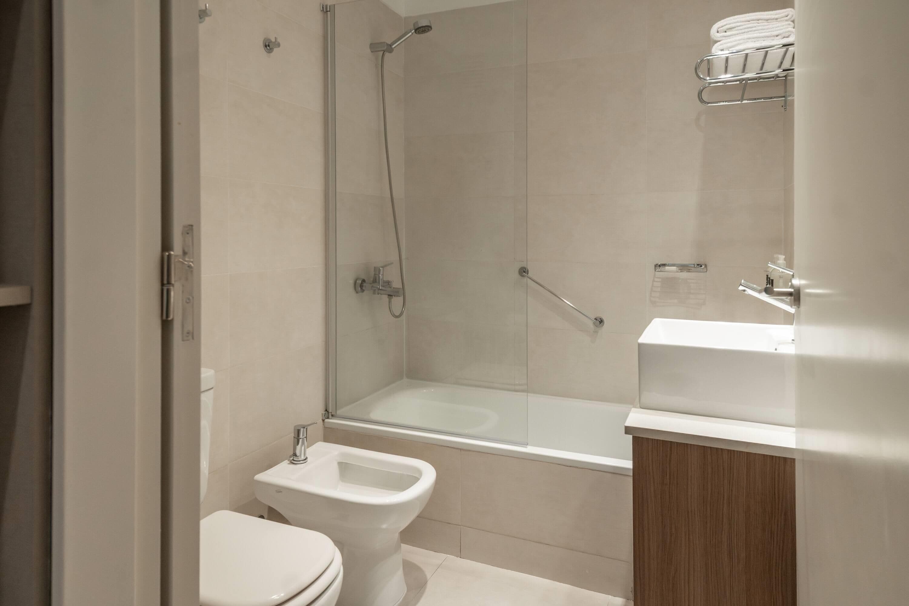 A modern bathroom with a glass shower enclosure, a toilet, and a sink with a wooden cabinet.