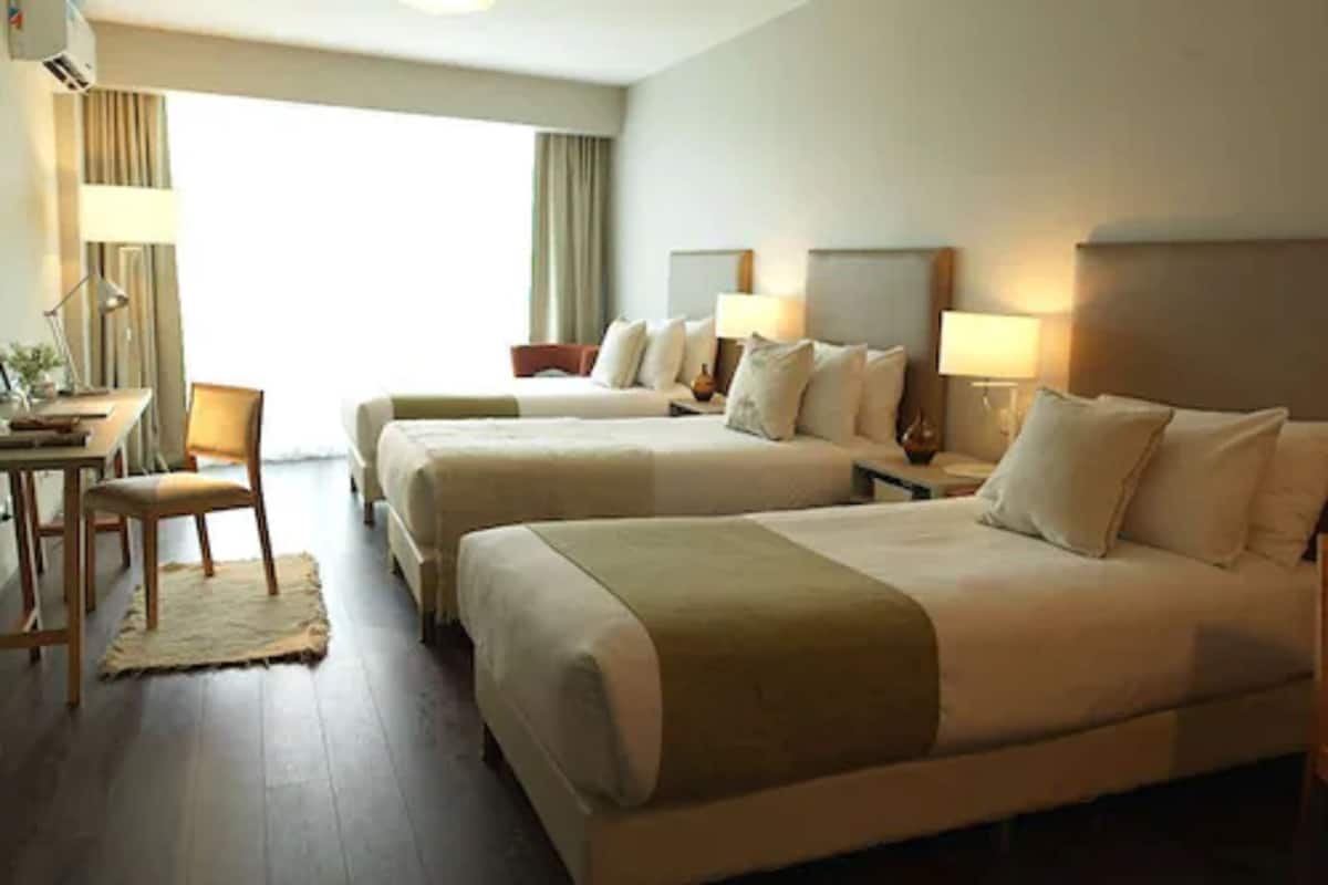 A hotel room with two beds, a desk, and a chair.