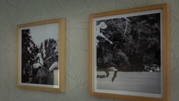 Twee ingelijste zwart-witfoto’s aan een muur, versierd met een bladmotief.