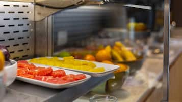 Un bufé con diversas frutas y un vaso de agua.
