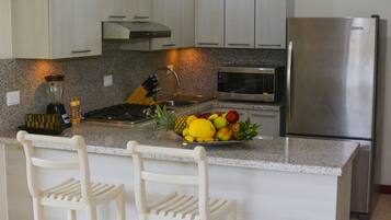 Una cocina con encimeras de granito, electrodomésticos de acero inoxidable y un frutero en la isla.