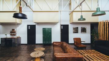 A spacious lobby with a leather sofa, wooden tables, and hanging pendant lights.