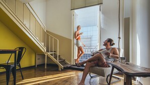 A room with a wooden floor, a staircase, a table, and a chair. - La Joya Hostel (Valparaiso)
