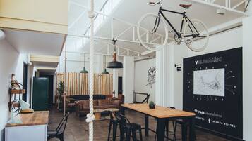 Un interior moderno con una mesa de comedor de madera, sillas negras, una bicicleta colgada y un mapa en la pared.