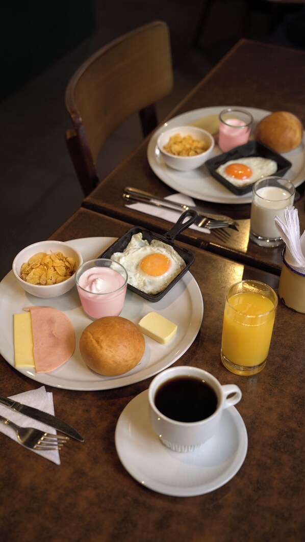 Una mesa de desayuno con platos de comida, una taza de café y un vaso de jugo de naranja.