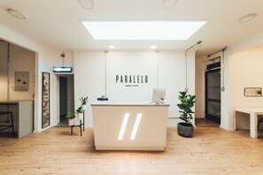 A modern reception desk with a minimalist design, a visible nameplate, and potted plants.