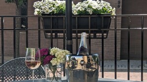 A table set outdoors with a bottle of champagne, a glass, and a vase with flowers. - La Banque Hotel (Homewood)