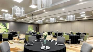 A conference room with round tables, chairs, and a chandelier.