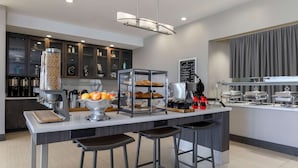 Une cuisine moderne dotée d’un îlot central, de tabourets de bar, d’une machine à café et de divers appareils de cuisine.