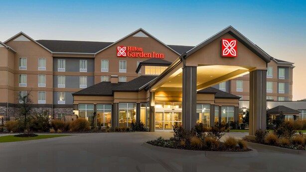 Un hôtel Hilton Garden Inn au design moderne, doté d’un grand auvent à l’entrée et d’une façade bien éclairée.