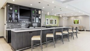 Une cuisine moderne dotée d’un îlot central, de tabourets de bar et d’un coin repas avec des chaises.