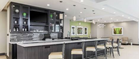 A modern kitchen with a central island, bar stools, and a dining area with chairs.