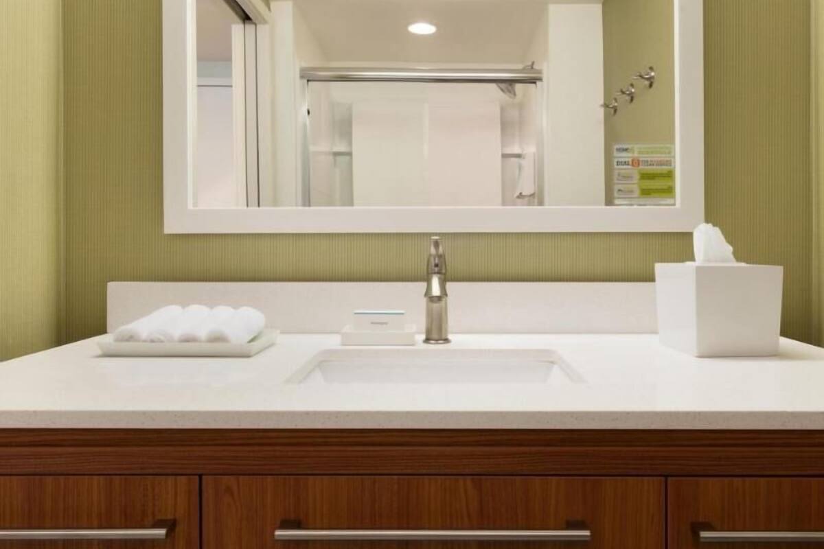 A bathroom with a white sink, a mirror, and a wooden vanity.