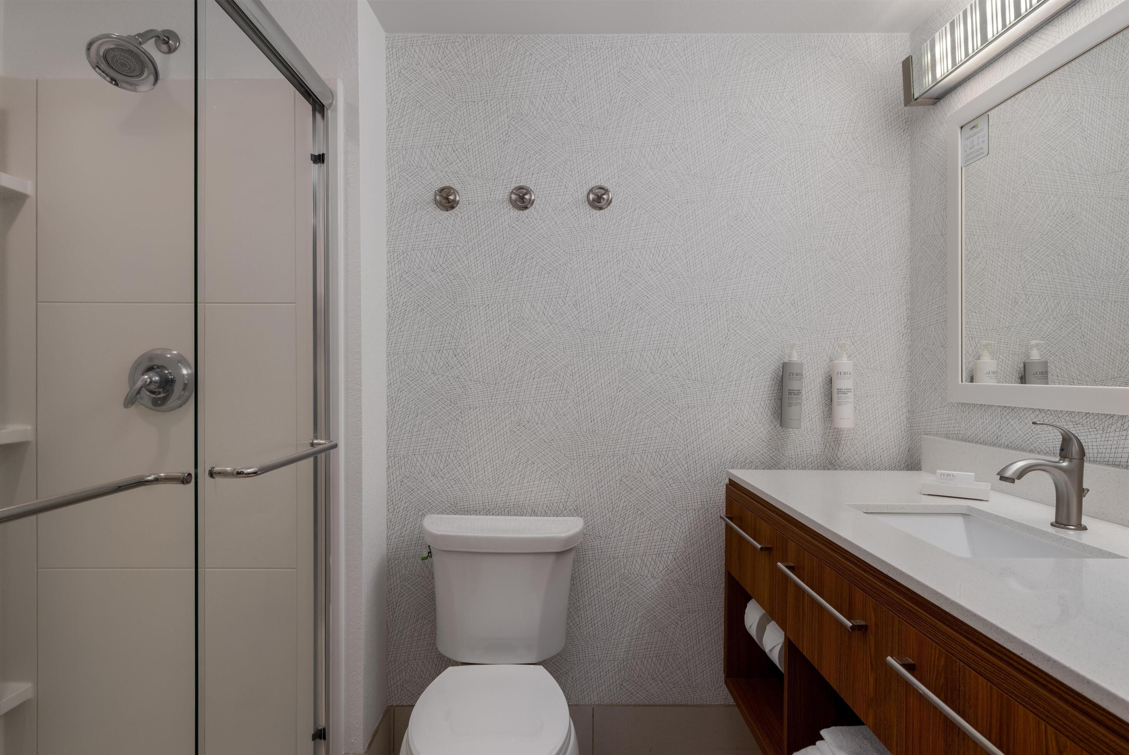 Een moderne badkamer met douche, toilet en wastafel.
