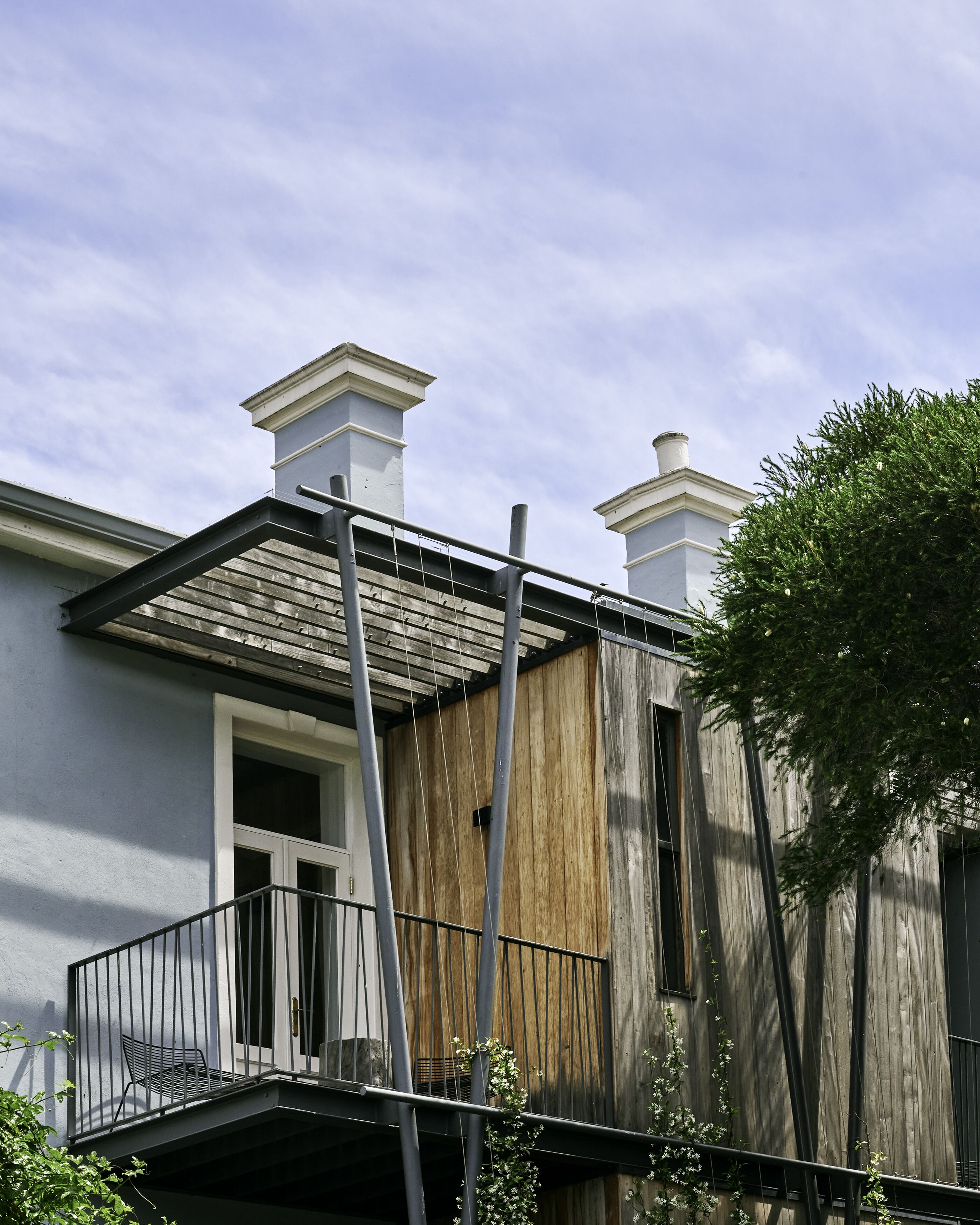 A residential building with a balcony, a wooden facade, and two chimneys.