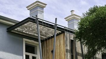 A residential building with a balcony, a wooden facade, and two chimneys.